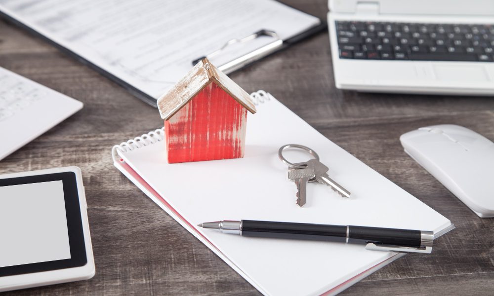 Wooden house model with a keys, pen and notepad