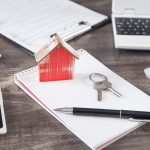 Wooden house model with a keys, pen and notepad