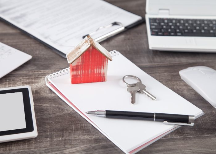 Wooden house model with a keys, pen and notepad